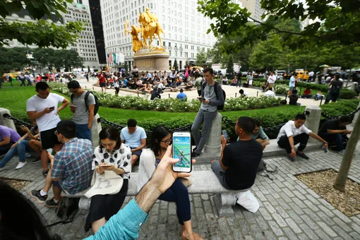 Жители Нью-Йорка играют в Pokemon Go в одном из городских парков, июль 2016 года